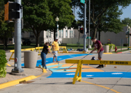 3 people painting bright colors onto pedestrian crosswalks in Morris, IL.