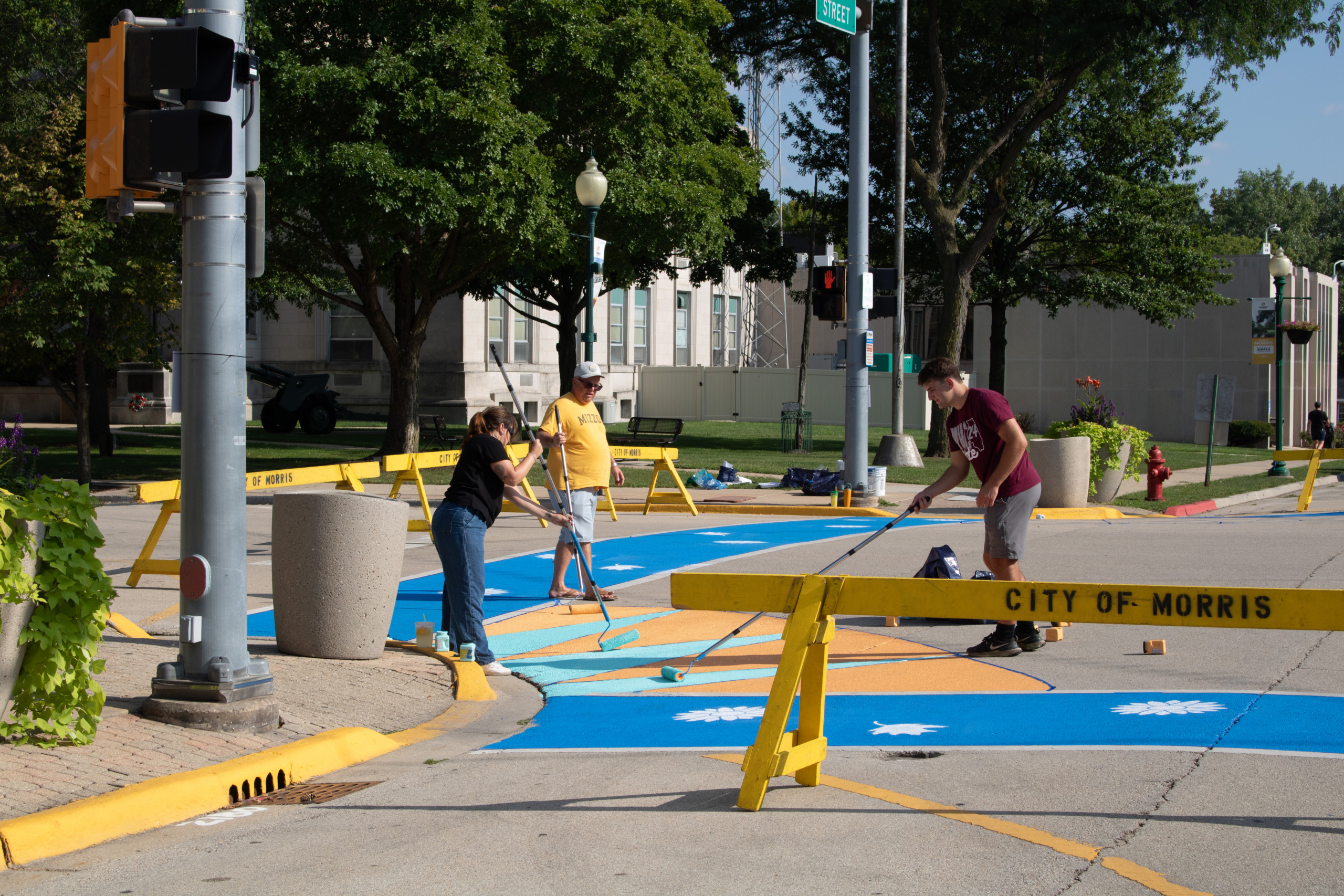 Antero and the City of Morris Paint Pedestrian Crosswalks 3 people painting bright colors onto pedestrian crosswalks in Morris, IL.